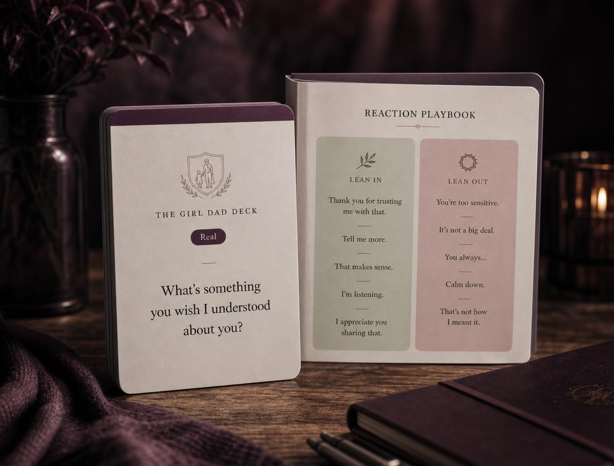 A playbook and phone on a lamp-lit nightstand at night.